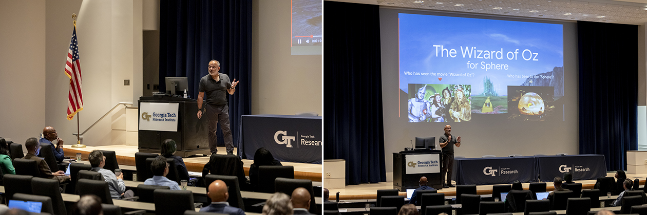 Presenter speaking to an audience in an auditorium, standing near a podium with Georgia Tech Research signage, with a large screen displaying a slide titled ‘The Wizard of Oz for Sphere’ featuring images from the movie.